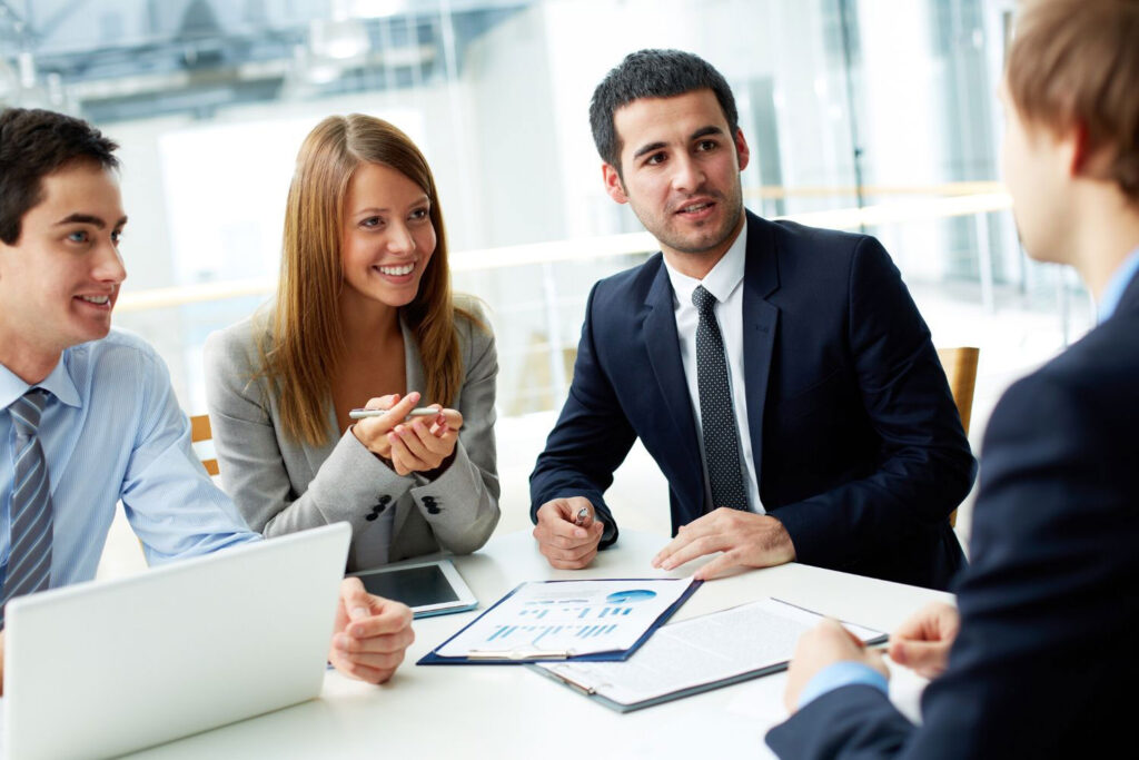 A group of people sitting at a table with papers.