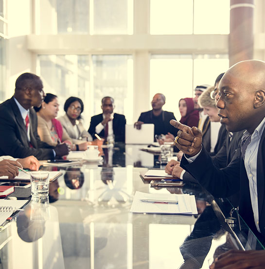 A group of people siting together on a large office table.